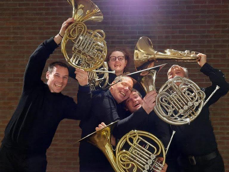5 muzikanten van het Klassiek hoornensemble the horn revival uit Malle houden hun hoorn in de lucht voor de foto.